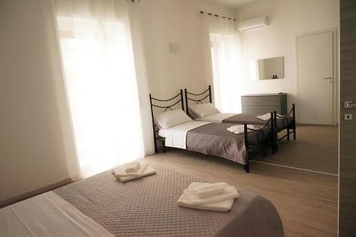 1 Schlafzimmer mit 2 Betten, einem Tisch und einem Spiegel in der Unterkunft LA RESIDENZA DI ADAMO in Syrakus