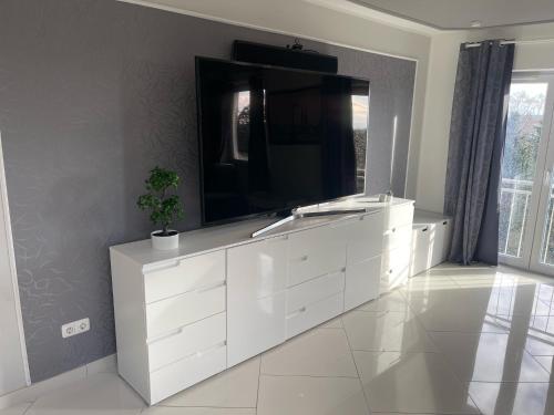 a white dresser with a television on top of it at InselSuites FinkenNest Airbus Finkenkwerder 125 m2 Kamin in Hamburg