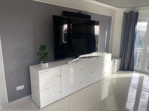 a white dresser with a television on top of it at InselSuites FinkenNest Airbus Finkenkwerder 125 m2 Kamin Whirpool in Hamburg