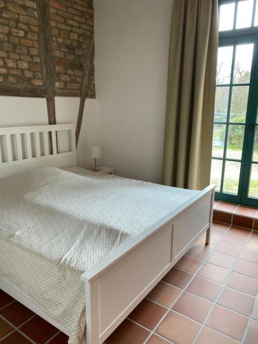ein weißes Bett in einem Zimmer mit einem großen Fenster in der Unterkunft Müllernhof in Faßberg