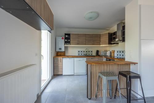 une cuisine avec des armoires en bois et un comptoir avec des tabourets dans l'établissement Rivage Calvados - A 500m de la plage, à Courseulles-sur-Mer