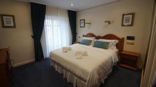 una habitación de hotel con una cama grande con dos tazas. en HOTEL RIAZA en Riaza