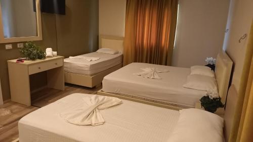 una camera d'albergo con tre letti e uno specchio di Veal Hotel and Restaurant a Tepelenë