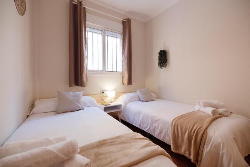two twin beds in a room with a window at Los Cármenes in Algeciras