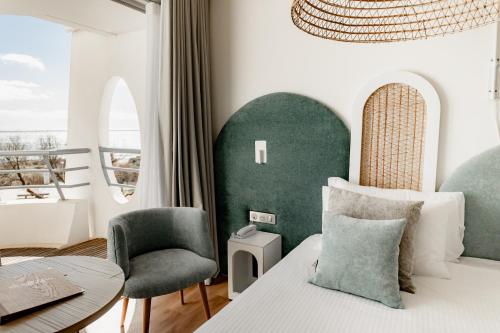 a bedroom with a bed and a chair and a table at Hôtel Les Corallines - Thalasso & Resort in La Grande-Motte