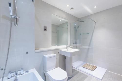 a white bathroom with a toilet and a sink at Hestia Travel London in London