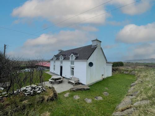 a small white house with a bench in a yard at Ballylusky Holiday Home by Trident Holiday Homes in Ballydavid