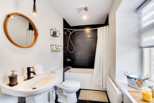 a bathroom with a sink and a toilet and a mirror at Maison Grenier - Le Loft in Quebec City