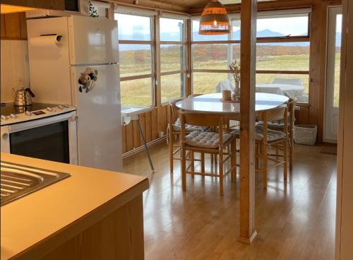 een keuken met een tafel en een witte koelkast bij Hestaland Horse Farm Cottage in Borgarnes