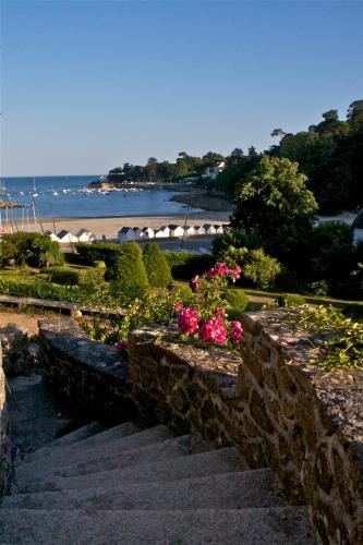 a set of stairs leading to a beach with pink flowers at Manoir Dalmore in Névez