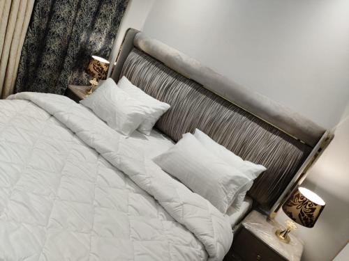ein Bett mit weißer Bettwäsche und Kissen in einem Schlafzimmer in der Unterkunft Premium&Cozy Two Beds DHA in Lahore