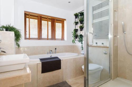 a bathroom with a tub and a toilet and a sink at Serene Riverside: 6BR Luxury Retreat in Curdridge in Curdridge