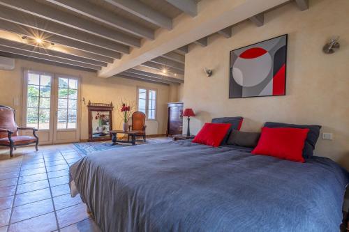 a bedroom with a large bed with red pillows at Maison coeur de Bastide-Piscine, ping pong & salle de jeux in Vianne