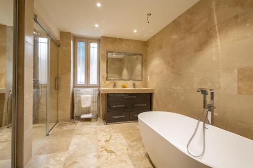 a bathroom with a tub and a sink and a mirror at Maison coeur de Bastide-Piscine, ping pong & salle de jeux in Vianne