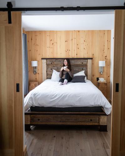 a woman sitting on top of a bed at Le Grand R in Saint-Donat-de-Montcalm