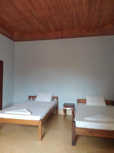 two beds in a room with a wooden ceiling at Green Hill Homestay, Restaurant & Treķking in Banlung