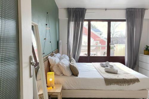 a bedroom with a large bed with a window at Le Syrme • 450m de la plage, balcon & parking in Annecy