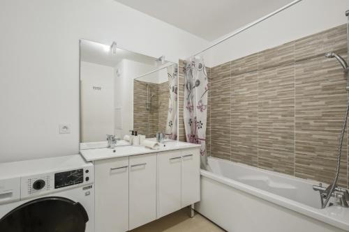 a bathroom with a sink and a tub and a washing machine at Chic and spacious apart with parking in Cergy