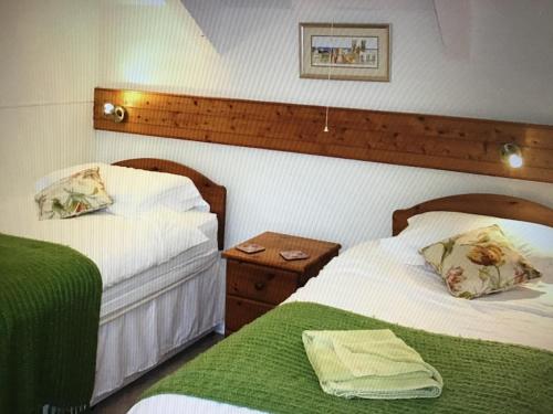 - une chambre avec 2 lits et une tête de lit en bois dans l'établissement Holiday Cottage Cornwall, à Delabole