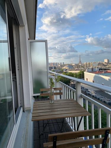 a balcony with a wooden bench and a view of the city at Rosewood Rooftop Eiffel Paris Porte de Versailles in Issy-les-Moulineaux