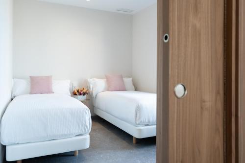 a room with two white beds and a chair at ASA Hotel La Marina in Ondara