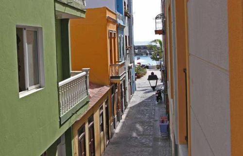 an alley between two buildings with a person riding a bike at Apartment Océano in Puerto de Tazacorte