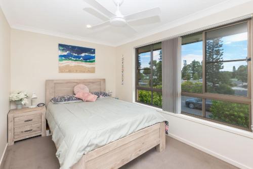 a bedroom with a bed with a fan and windows at Hibbard 24 in Port Macquarie