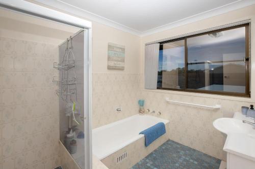 a bathroom with a bath tub and a sink at Hibbard 24 in Port Macquarie