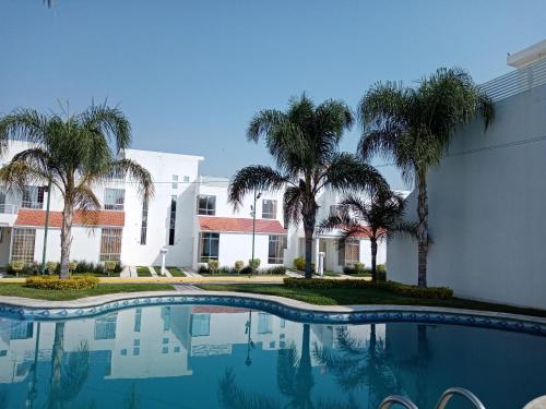a swimming pool in front of a building with palm trees at LINDA CASA DE DESCANSO EN MORELOS in Cuautla Morelos