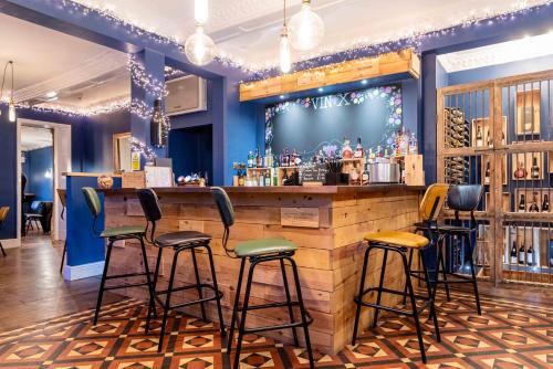 un bar con taburetes en una habitación con paredes azules en Three Ways House Hotel en Chipping Campden