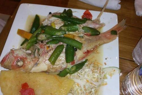 a plate of food with fish and vegetables on a table at Gated Cozy Urban Luxe Retreat in Portmore