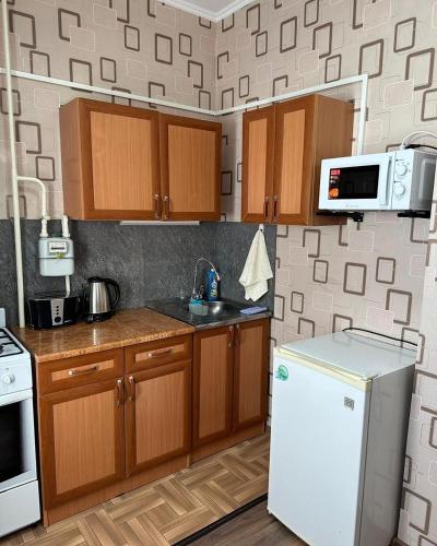 uma cozinha com armários de madeira e um frigorífico branco em EASY RenT Taraz em Taraz