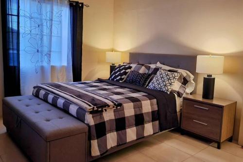 a bedroom with a bed and a table with a lamp at Gated Cozy Urban Luxe Retreat in Portmore