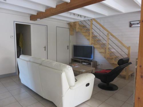 een woonkamer met een witte bank en een televisie bij Clos Saint Hilaire in Longeville-sur-Mer
