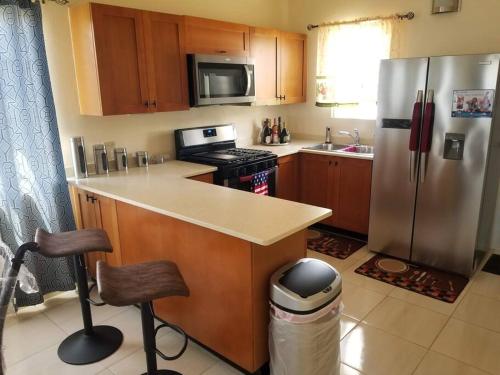 a kitchen with a stainless steel refrigerator and a counter at Gated Cozy Urban Luxe Retreat in Portmore