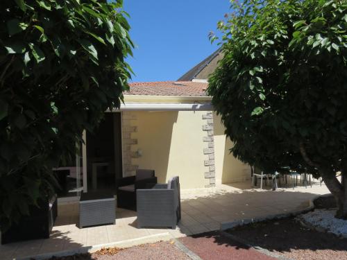 een wit huis met stoelen en een boom bij Clos Saint Hilaire in Longeville-sur-Mer