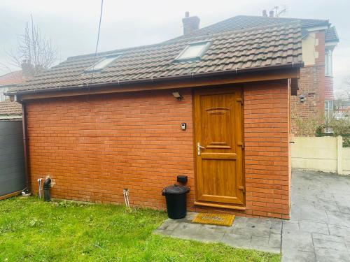 een klein bakstenen huis met een houten deur bij Private guest house/Annexe in Manchester