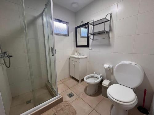 een badkamer met een toilet en een glazen douche bij Cálida Cabaña en el Corazón de Ushuaia in Ushuaia