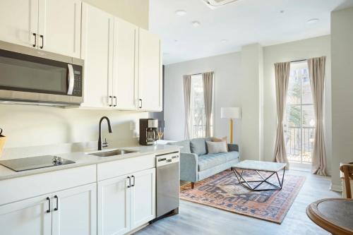 a kitchen with white cabinets and a living room with a couch at Roami at Canal Quarters in New Orleans