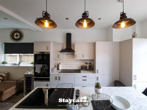 a kitchen with white cabinets and a table at Spacious 6-Bed with Large Patio and Free Parking in Manchester