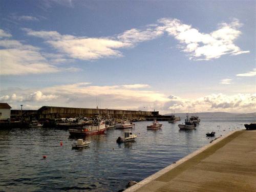 eine Gruppe von Booten im Wasser in der Nähe eines Docks in der Unterkunft Dachwohnung mit Terasse und Meerblick unweit des Strandes in Malpica
