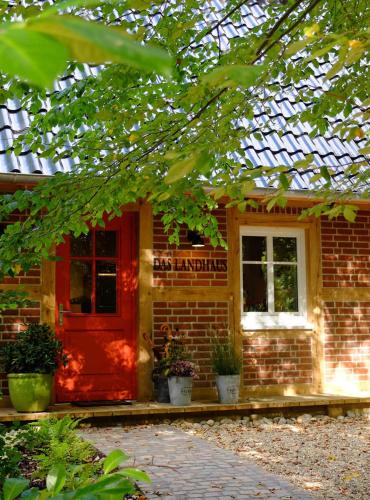 a brick house with a red door and windows at Das Landhaus in Bilsen
