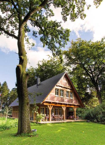 a large wooden house with a tree in the yard at Das Landhaus in Bilsen