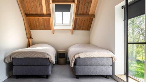 twee bedden in een kleine kamer met een raam bij Hello Zeeland - Vakantiewoning Hoeve De Lente in Breskens