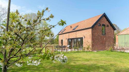 een stenen huis in een tuin met een boom bij Hello Zeeland - Vakantiewoning Hoeve De Lente in Breskens