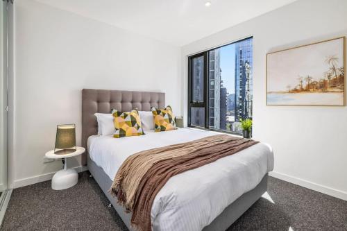um quarto com uma cama grande e uma janela grande em Modern Urban Oasis 2 bed Apartment em Melbourne