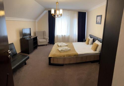 a hotel room with a bed and a chair and a television at Casa Bucegi in Bran