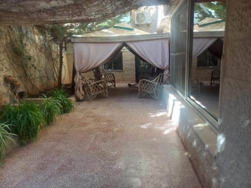 une terrasse avec une tente, des chaises et des plantes dans l'établissement شقه مفروشه مع حديقه اربد بجانب مدارس دار العلوم, à Irbid