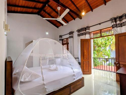 a bed with a white canopy in a room at Lavish Lodge, Tangalle, Sri Lanka in Tangalle