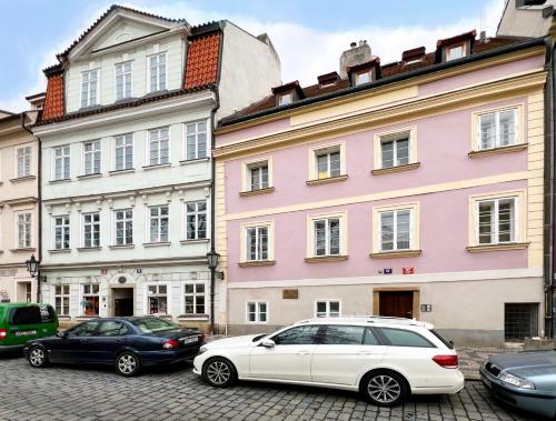 プラハにあるレジデンス カレル ブリッジのピンクの建物の前に駐車した白車